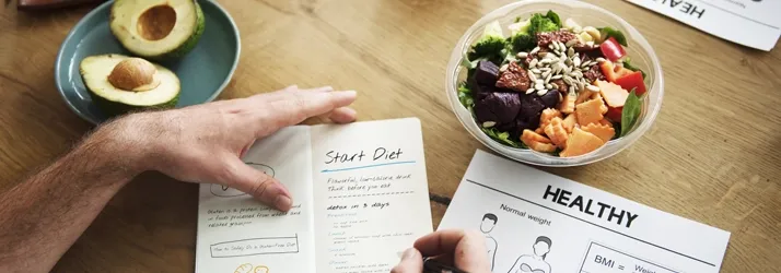 A man meal planning and working on a nutrition journal