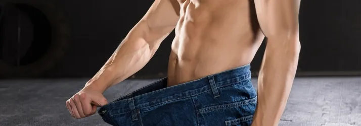 A man showing off weight loss results in oversized jeans